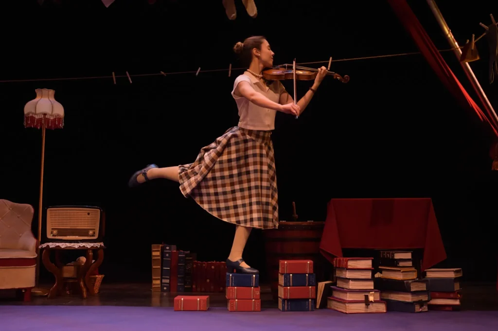 Froufrou toca el violín entre libros en LLOC, buscando encajar